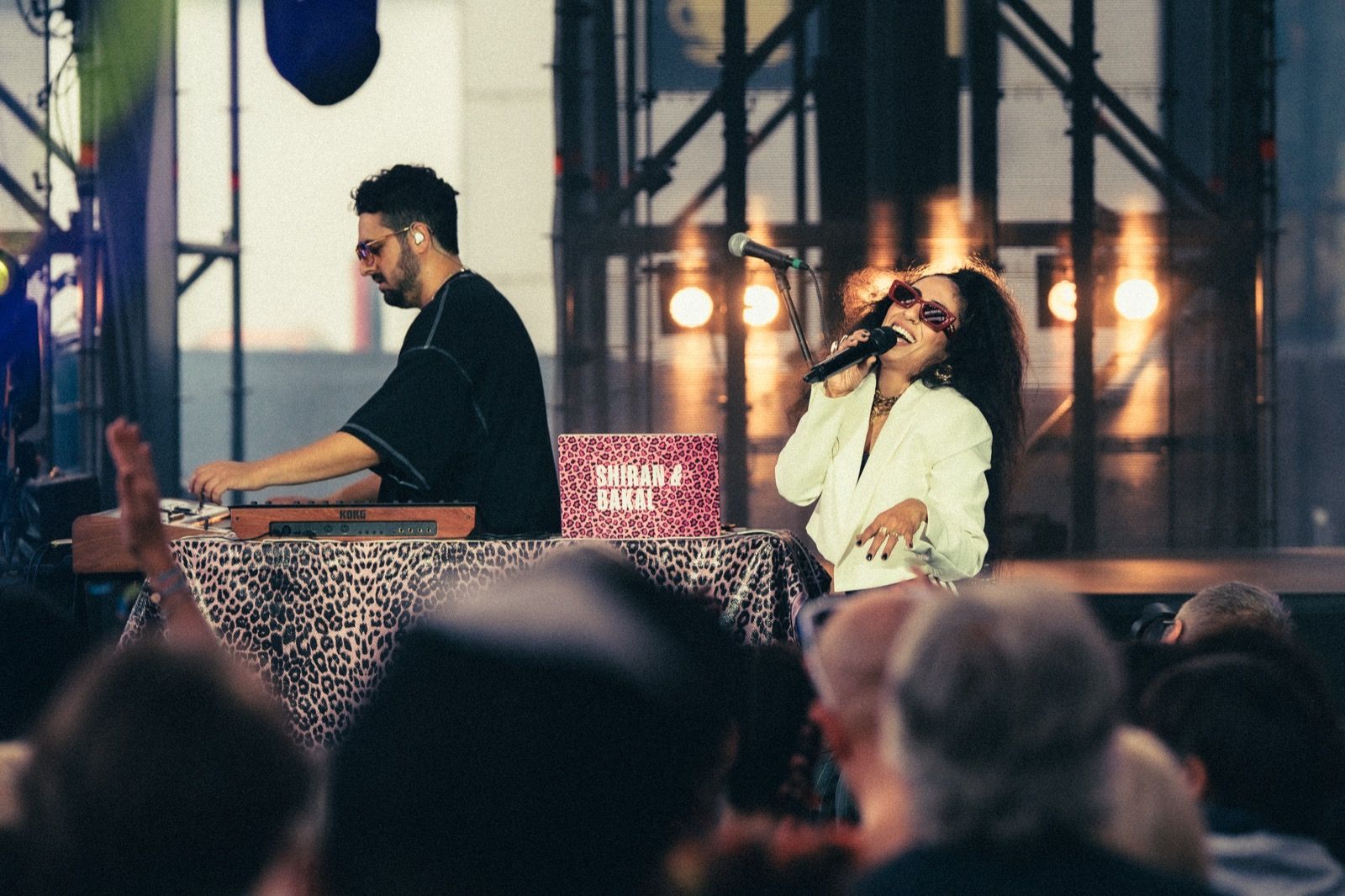 Eine Sängerin am Mikrofon neben einem Keyboarder auf einer Open-Air-Bühne.